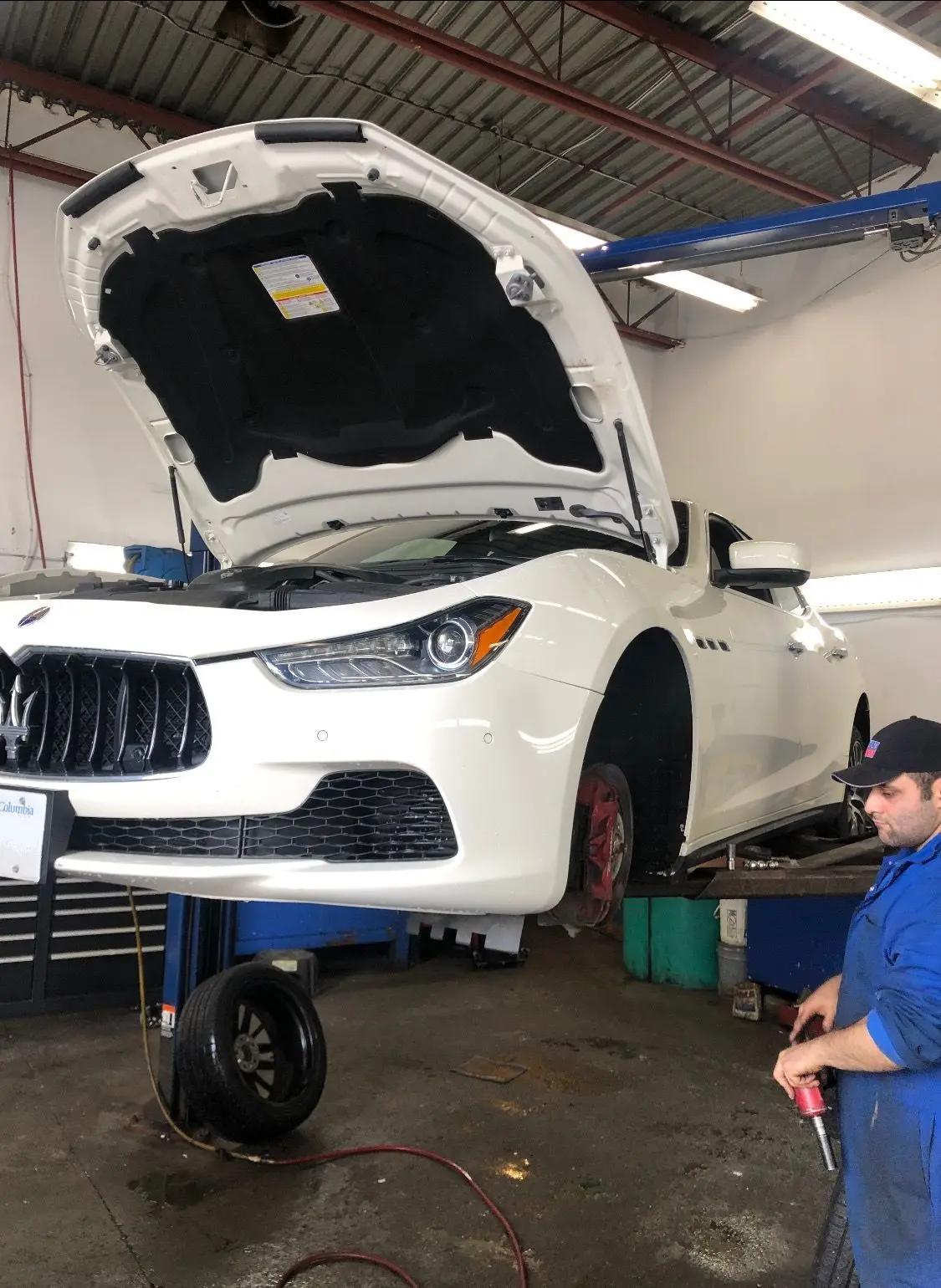 White Maserati on a lift with the hood open at KMF Automotive